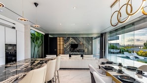 Una cucina moderna con piano di marmo, forno integrato e zona pranzo con parete vetrata vista piscina.