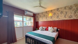 Habitación de hotel con cama, cortinas, ventilador de techo, aire acondicionado y ventana con vista a edificios.