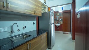 A kitchen with wooden cabinets, a stainless steel refrigerator, and a sink. - Sancta Monica Lounge -Cochin Airport  (Nedumbassery)