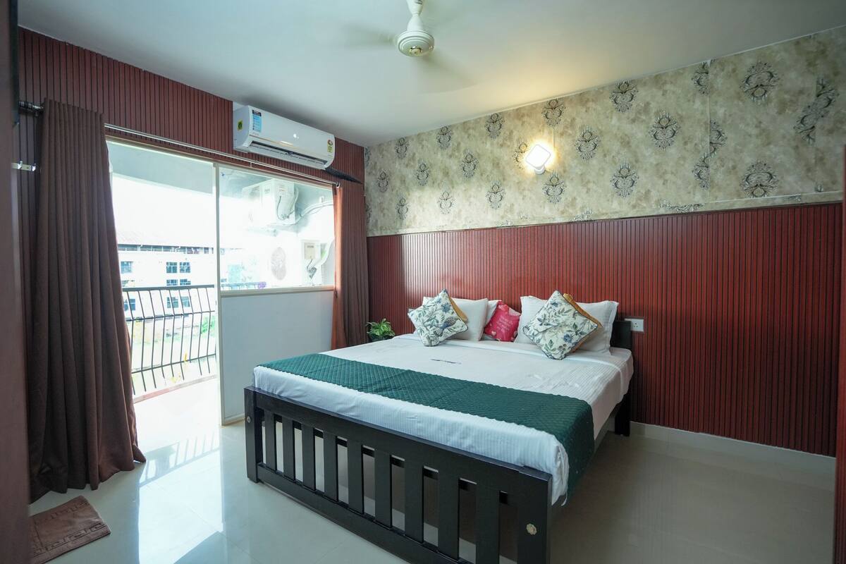 A bedroom with a bed, a window with curtains, a ceiling fan, and a wall-mounted air conditioner.