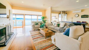 A spacious living room with a pool table, a sofa set, and a view of the sea through large windows. - StayAU · The River House · Paradise Pet-friendly (Beauty Point)