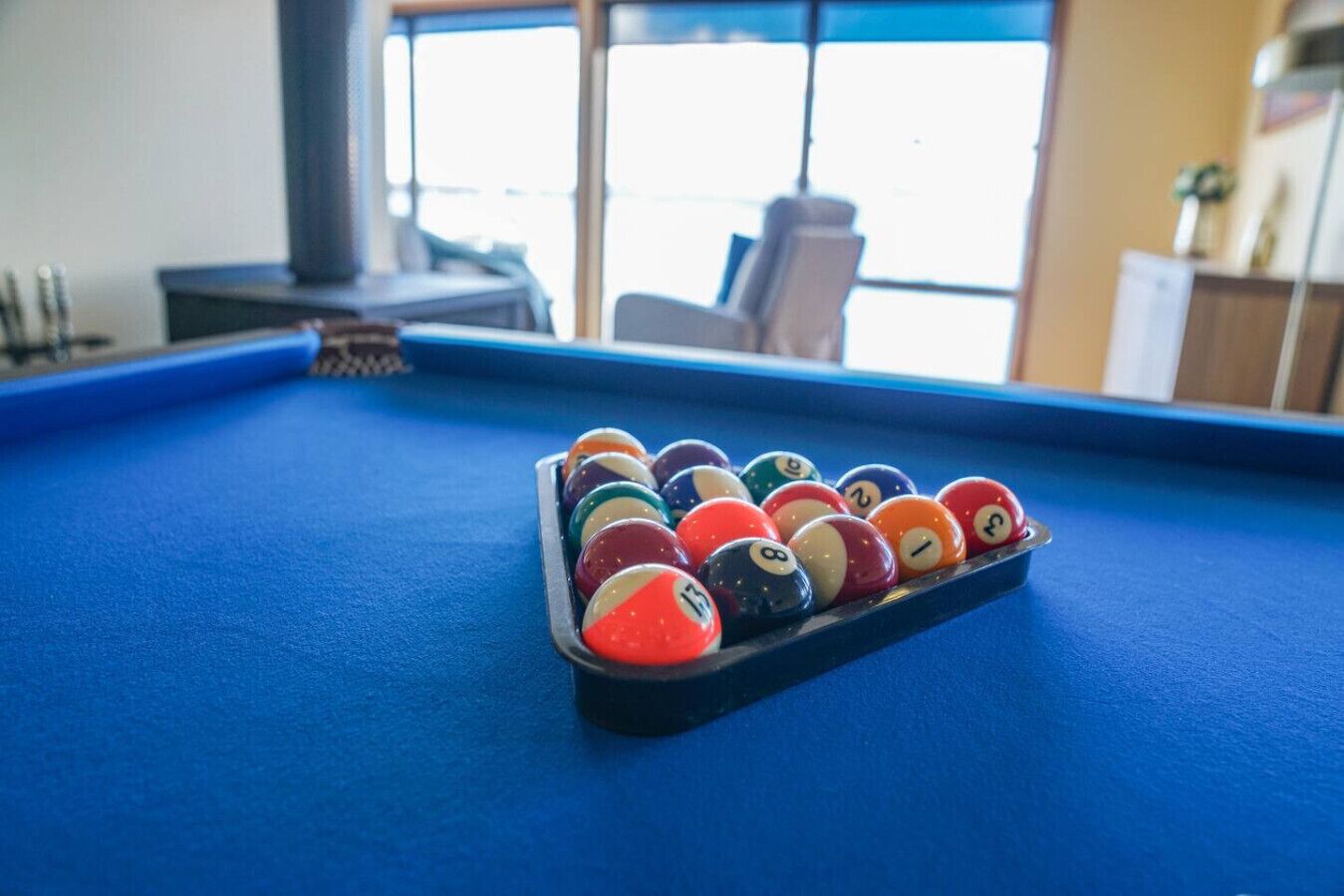 Ein Billardtisch mit blauer Spielvliesdecke und einer Pyramide aus Billardkugeln.