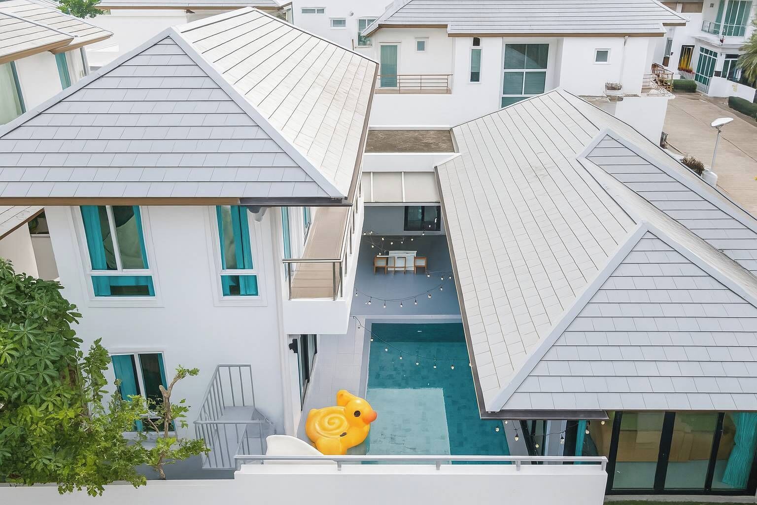 Un edificio residencial con piscina en la azotea, un pequeño espacio para sentarse al aire libre y una escalera visible.
