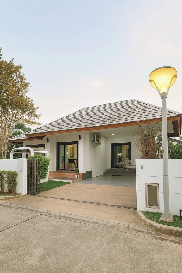 A modern house with a covered porch, a driveway, and a street lamp.