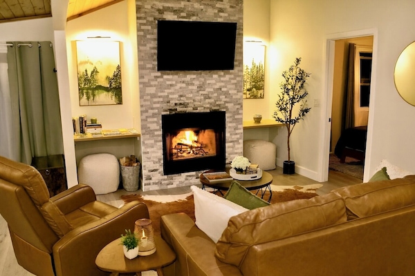 Modern living room with stone fireplace, Smart TV & forest views