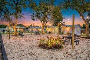 Un terrain de camping doté de plusieurs cabanes, de tables de pique-nique et de guirlandes lumineuses.