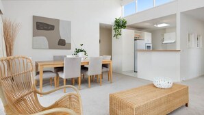 Un espace de vie moderne et minimaliste comprenant un coin repas, une cuisine et une grande fenêtre.