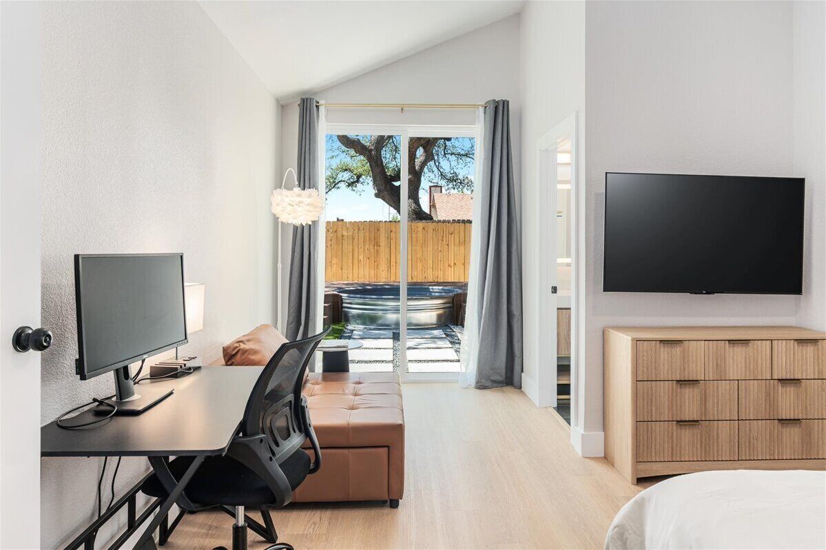 A modern hotel room with a desk, chair, and TV.