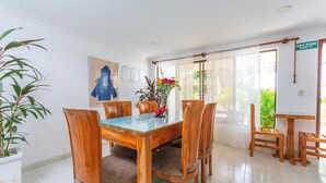 Een eetgedeelte met een houten tafel en stoelen, een kamerplant en uitzicht op het omliggende landschap door een raam.