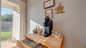 A kitchen counter with a coffee maker, jars of sugar and coffee, and a mug with a quote.