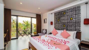 A hotel room with a bed, a balcony, a wall with a geometric pattern, and a view of palm trees.