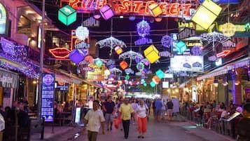 A bustling street with colorful neon signs and a crowd of people.