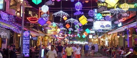 A bustling street with colorful neon signs and a crowd of people.