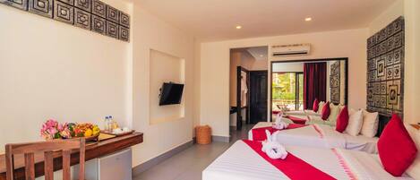 A hotel room with two beds, a desk with a TV, and a small kitchenette.