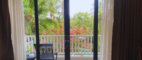 A balcony with a chair and a table, overlooking a garden with various plants and flowers.