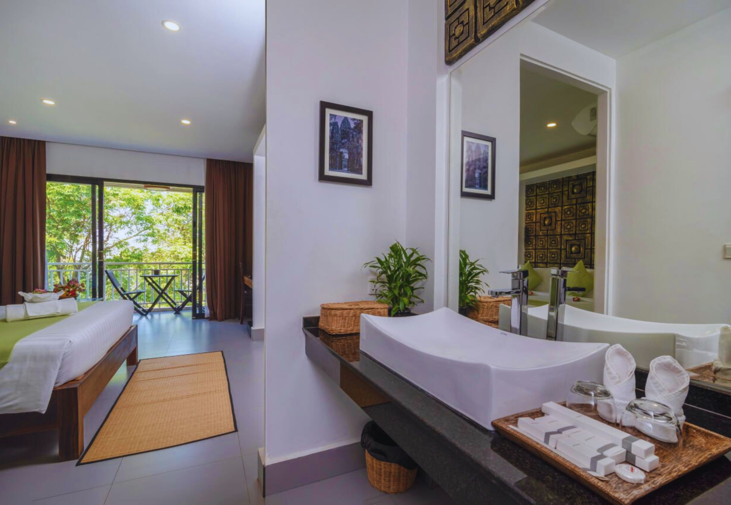 Une chambre d’hôtel moderne dotée d’un balcon, d’un grand lit, d’une salle de bain avec baignoire et d’un coin repas.