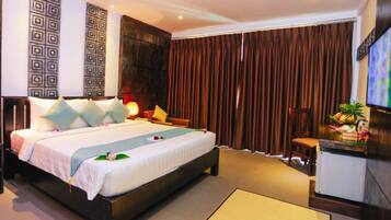 A modern hotel room with a large bed, a desk, a television, and a decorative wall panel.