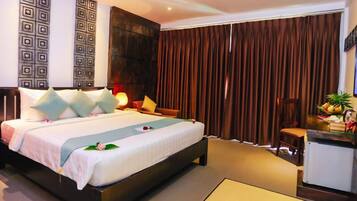 A hotel room with a bed, bedside table, lamp, and a view of the outside.