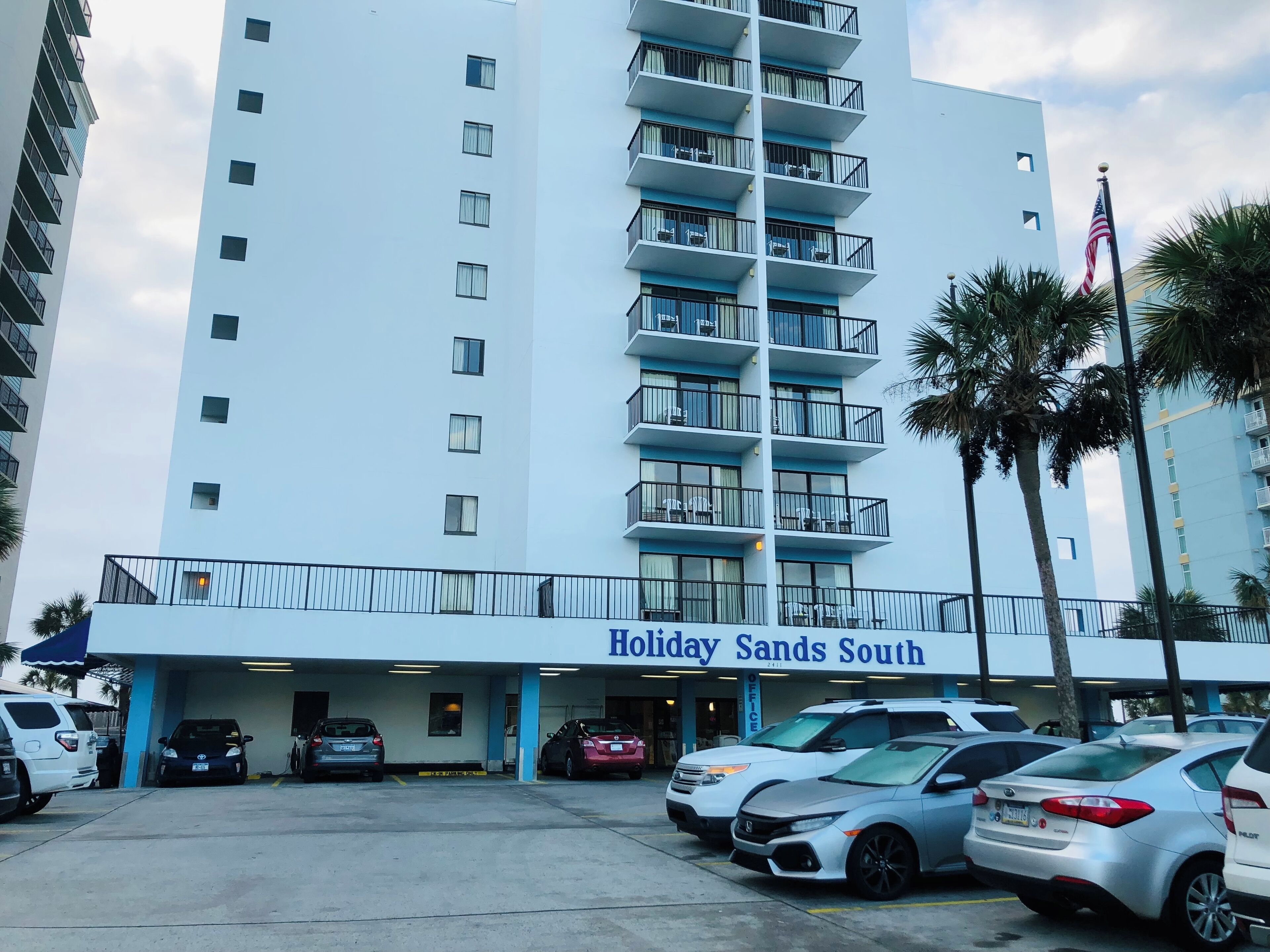 A multi-story hotel with a parking lot in front.