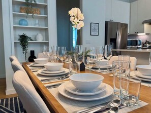 A dining area with a wooden table set for a meal, surrounded by chairs.