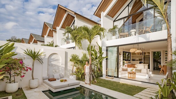 Una casa moderna con piscina, mobiliario exterior y un gran ventanal que da a una sala de estar.