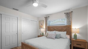 A bedroom with a wooden bed, two nightstands, a ceiling fan, and a window with curtains.