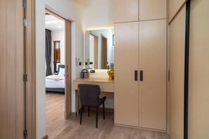 Een hotelkamer met een houten garderobe, een bureau met stoel, een bed met hoofdeinde en een grote spiegel.
