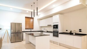 A modern kitchen with a central island, stainless steel appliances, and white cabinetry. - 3Bed SeaViewVilla FishermanVillage KBR43 (Koh Samui)