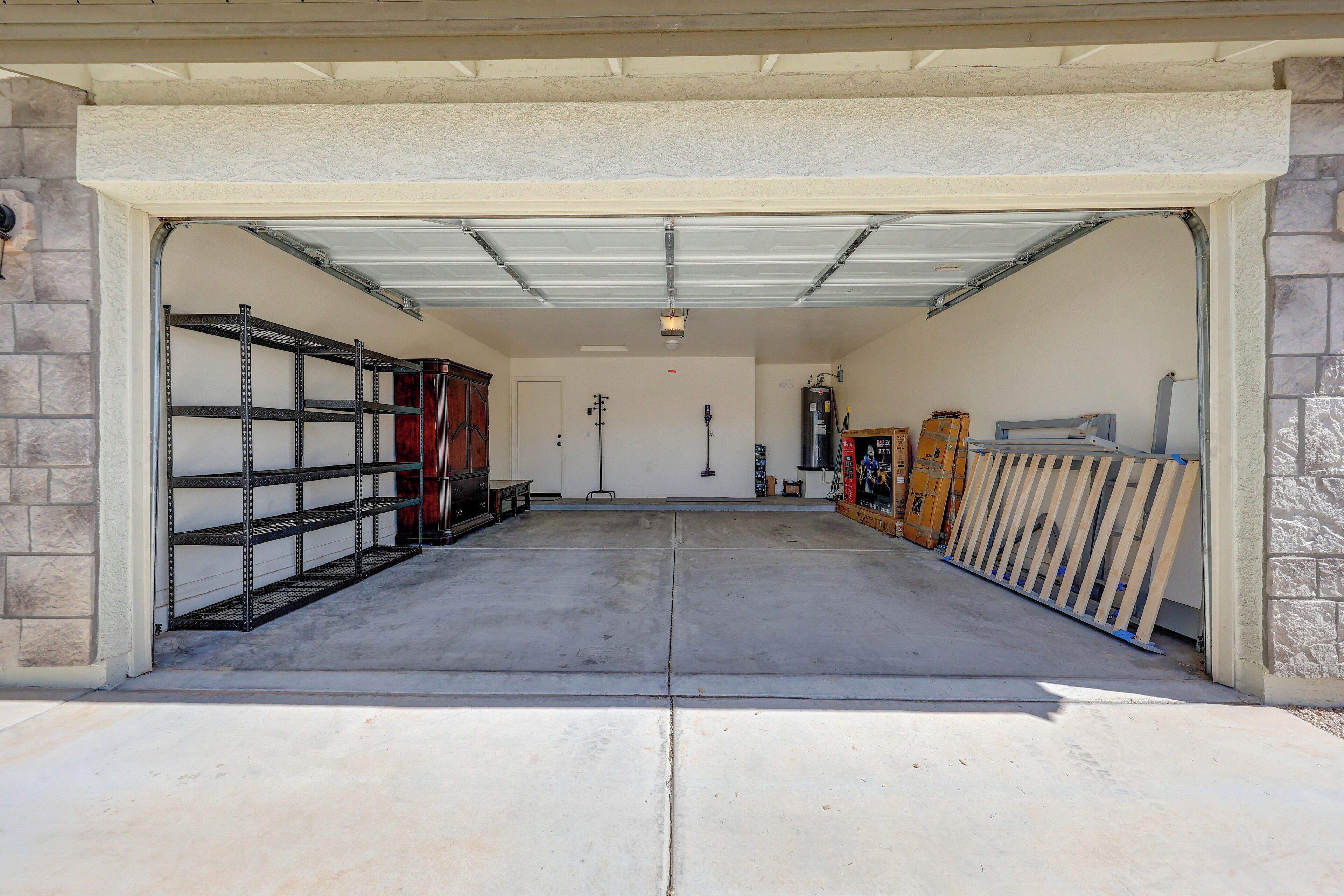A garage with a concrete floor, metal shelving units, and a wooden fence.