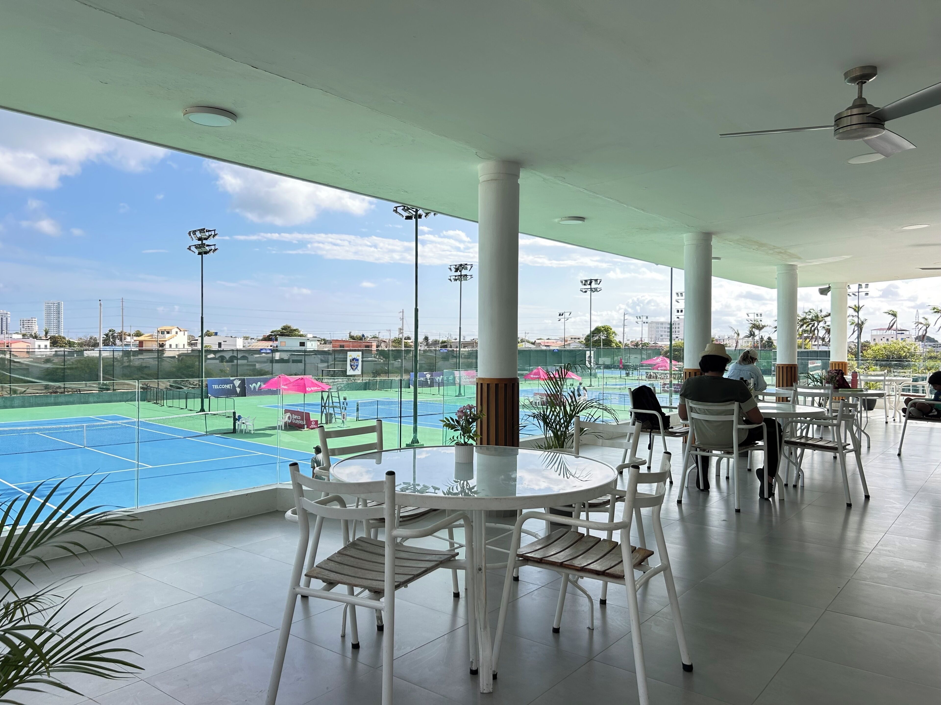 An indoor seating area with a view of a tennis court.