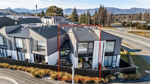 Uma casa moderna de dois andares com uma varanda grande, entrada para carros e uma rua com placa de limite de velocidade.