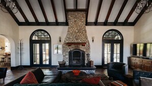 A spacious living room with a stone fireplace, leather sofas, and a television.