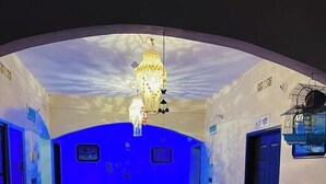 Une pièce avec un mur éclairé en bleu, un lustre, une table à manger avec des chaises et un canapé.