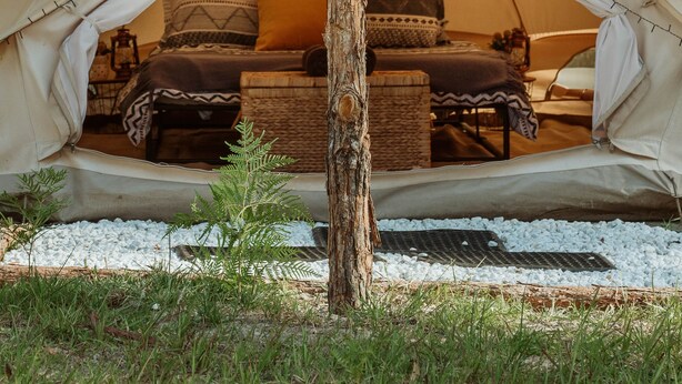 A tent with a central support pole, a bed with pillows, and a woven basket. - Romantic Queen Bed Glamping Tent (Tomerong)