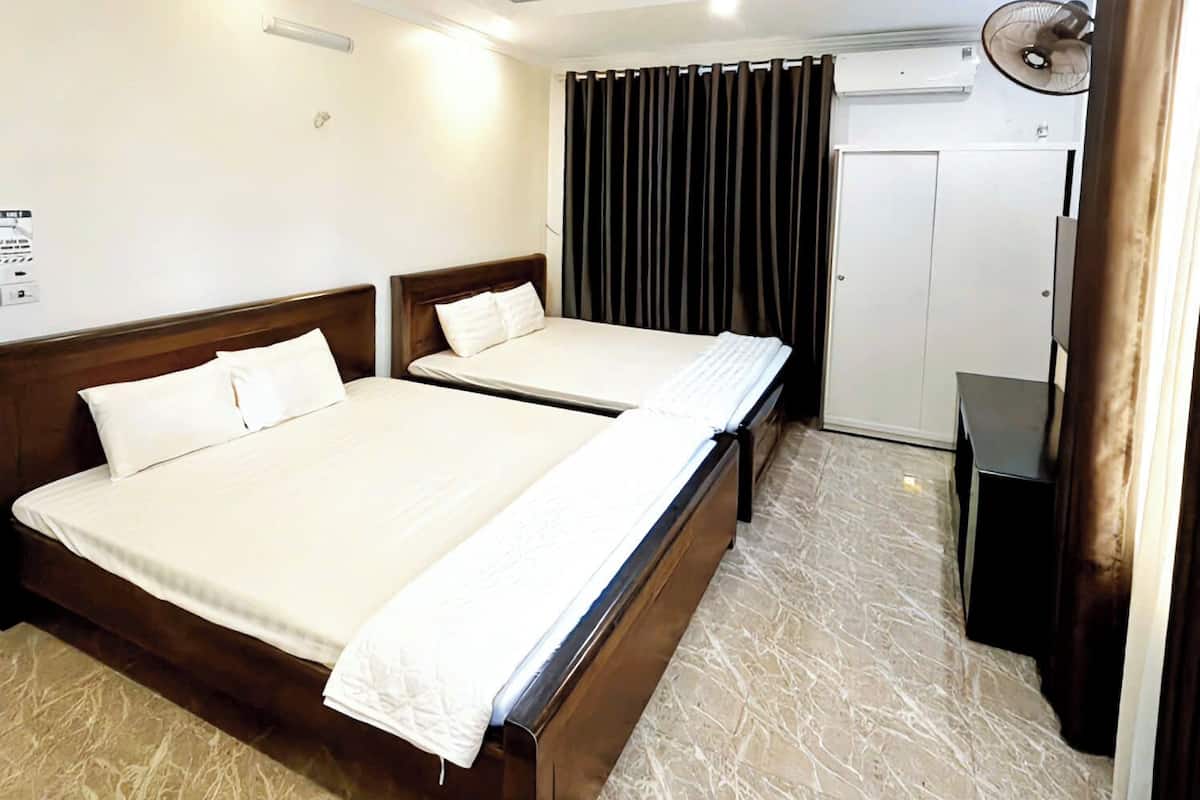 Habitación de hotel con dos camas, un escritorio, un armario y un ventilador de techo.