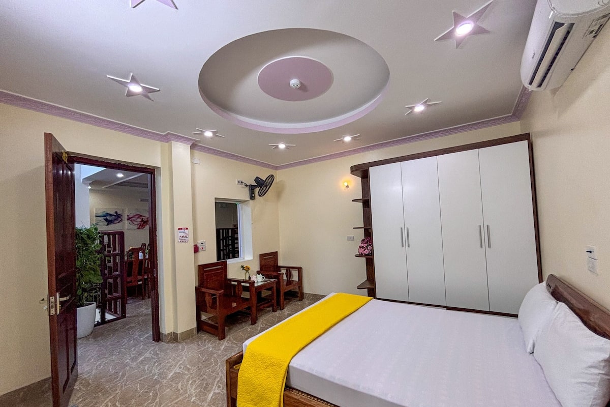 Un dormitorio con cama, armario, ventilador de techo y un área de comedor con sillas y mesa.