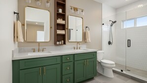 A modern bathroom with two sinks, a toilet, and a glass-enclosed shower.