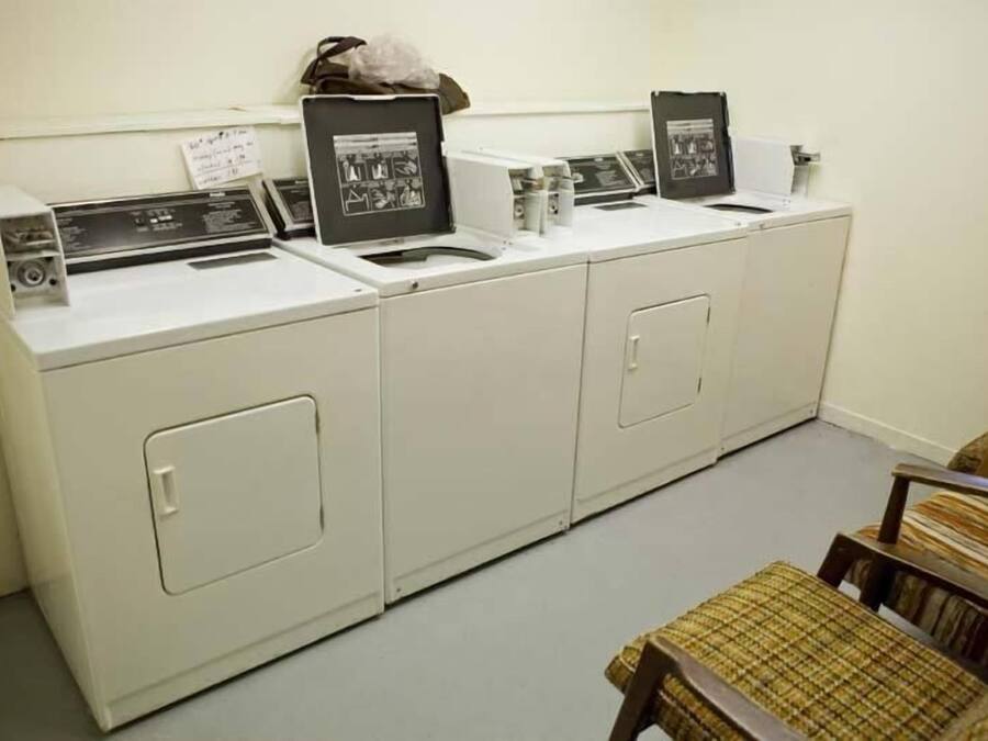 Une buanderie équipée de quatre machines à laver, d’un étendoir et d’une chaise.