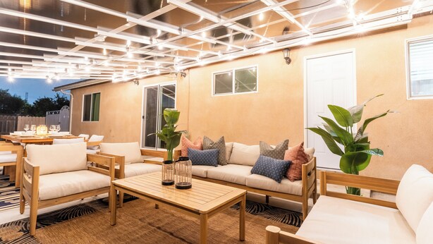 Un espace extérieur accueillant, aménagé avec du mobilier en bois, une table et des plantes en pot.