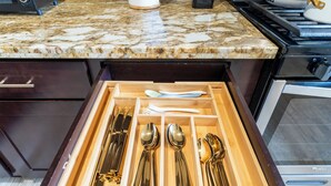 Un tiroir contenant des ustensiles de cuisine rangés avec soin, notamment des cuillères, des fourchettes et des couteaux.