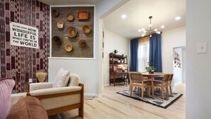 A living room with a sofa, a dining area with a table and chairs, and a wall with decorative baskets. - HostWise Stays - Firepit | Sauna | Driveway | Hammock | King Beds (Pittsburgh)