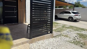 A modern building with a black metal gate, a white car parked outside, and a gravel driveway. - Spacious 3-bedroom house in serene Piedras Negras with AC and pool (Piedras Negras)