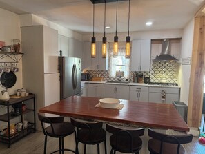 A modern kitchen with a central island, bar stools, a refrigerator, a microwave, and hanging pendant lights. - Spacious 3-bedroom house in serene Piedras Negras with AC and pool (Piedras Negras)