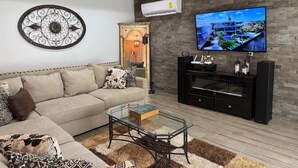 A modern living room with a beige sofa, a glass coffee table, a flat-screen TV, and a black entertainment unit. - Spacious 3-bedroom house in serene Piedras Negras with AC and pool (Piedras Negras)