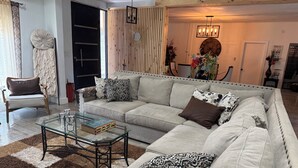 A living room with a beige sofa, patterned cushions, a glass coffee table, and a mirror on the wall. - Spacious 3-bedroom house in serene Piedras Negras with AC and pool (Piedras Negras)