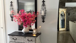 A vintage-style dresser with a mirror, pink flowers, and decorative wall sconces in a modern living room. - Spacious 3-bedroom house in serene Piedras Negras with AC and pool (Piedras Negras)