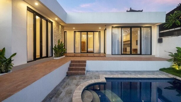 Una casa moderna con piscina, ampie finestre e una scala che conduce all'ingresso.