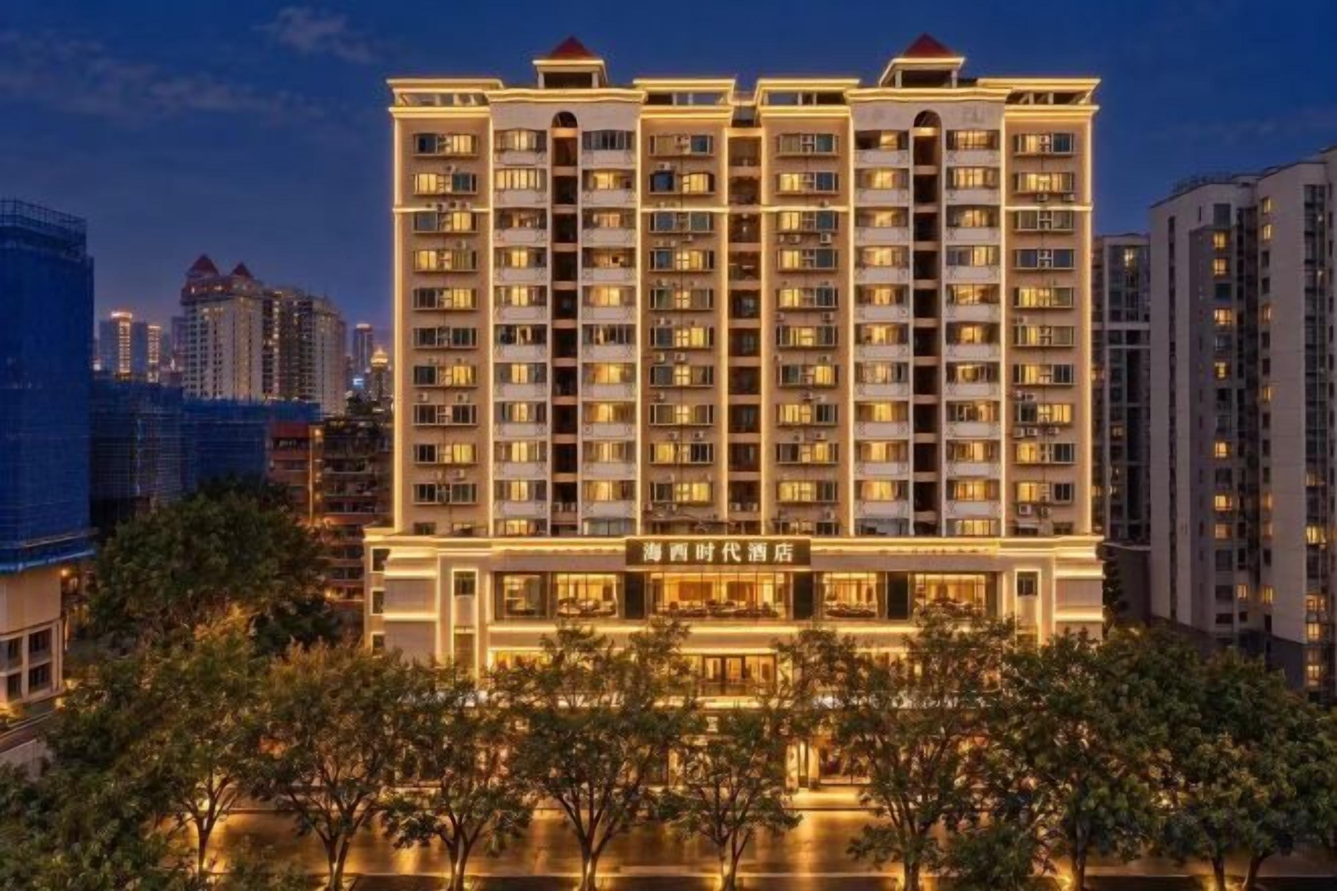 Monikerroksinen hotelli, jossa on näyttävä sisäänkäynti ja hyvin valaistu julkisivu.