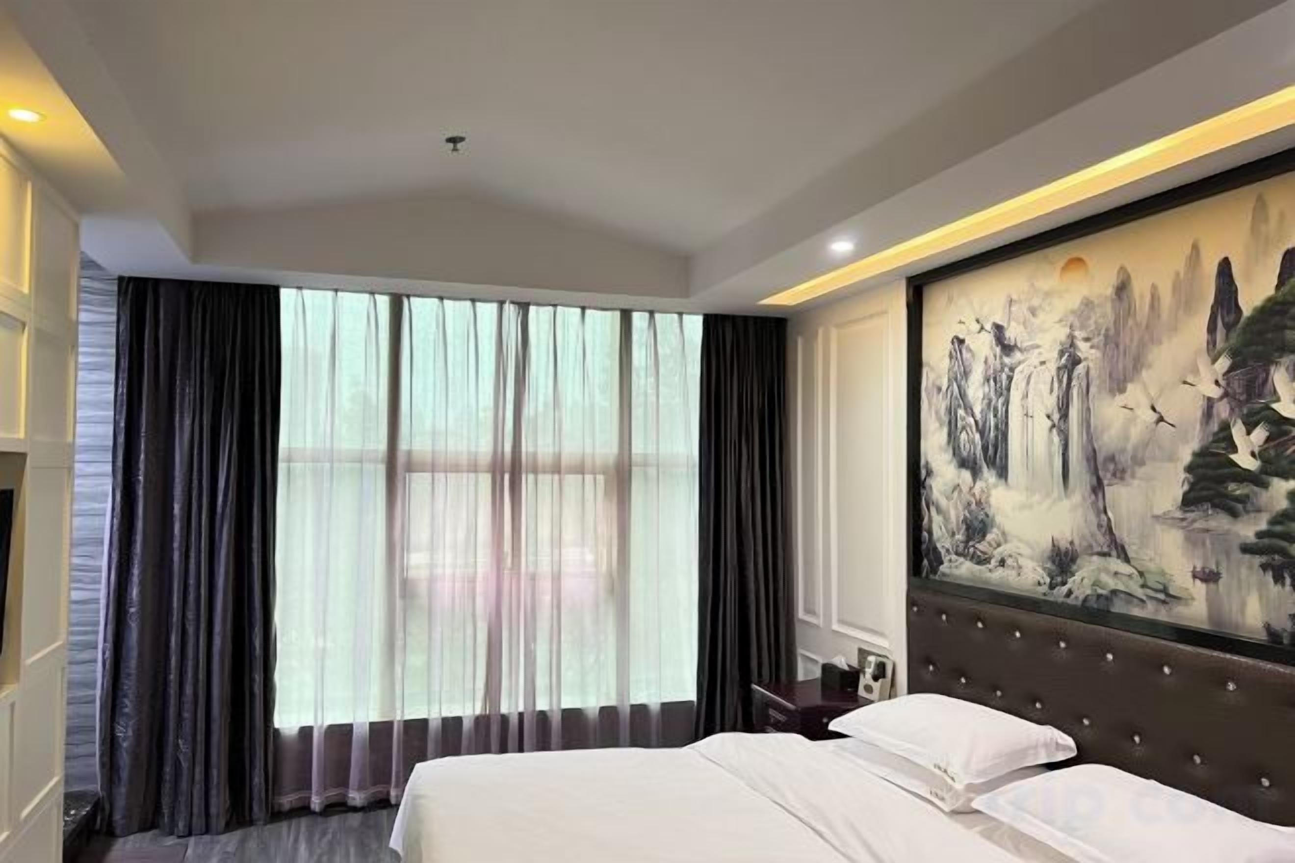 Habitación de hotel con una cama grande, un cuadro en la pared y una ventana con cortinas.