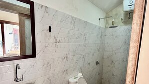 A bathroom with a marble-tiled wall, a stone sink, a white toilet, and a shower area. - Luma Guesthouse by Verdana Homes (Tibubeneng)